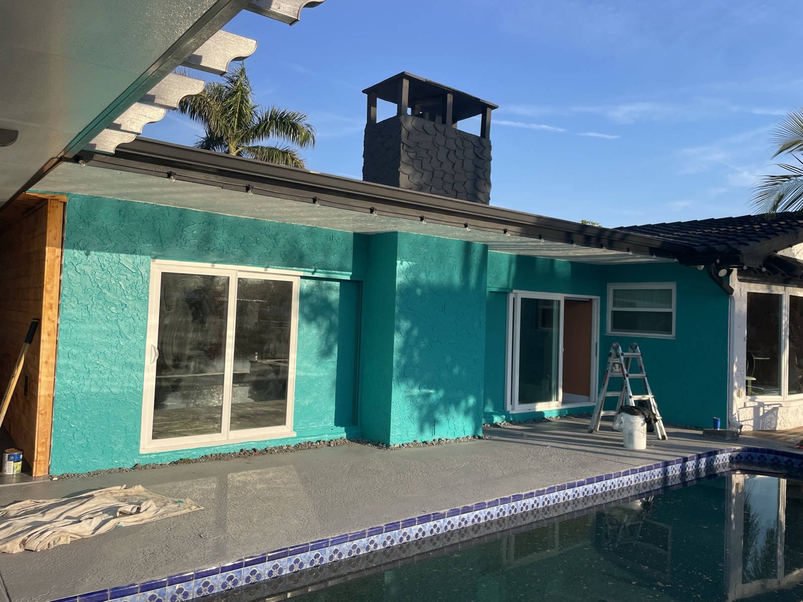 Teal waterfront poolside home after repaint
