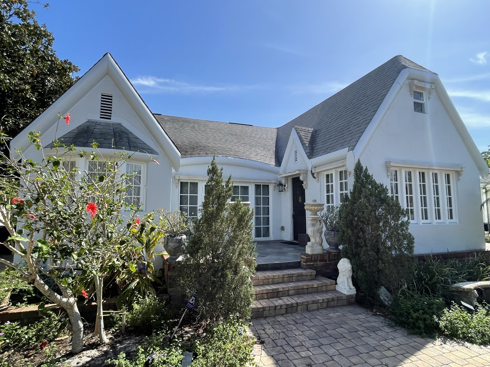White Tudor-style cottage with manicured landscaping after repaint
