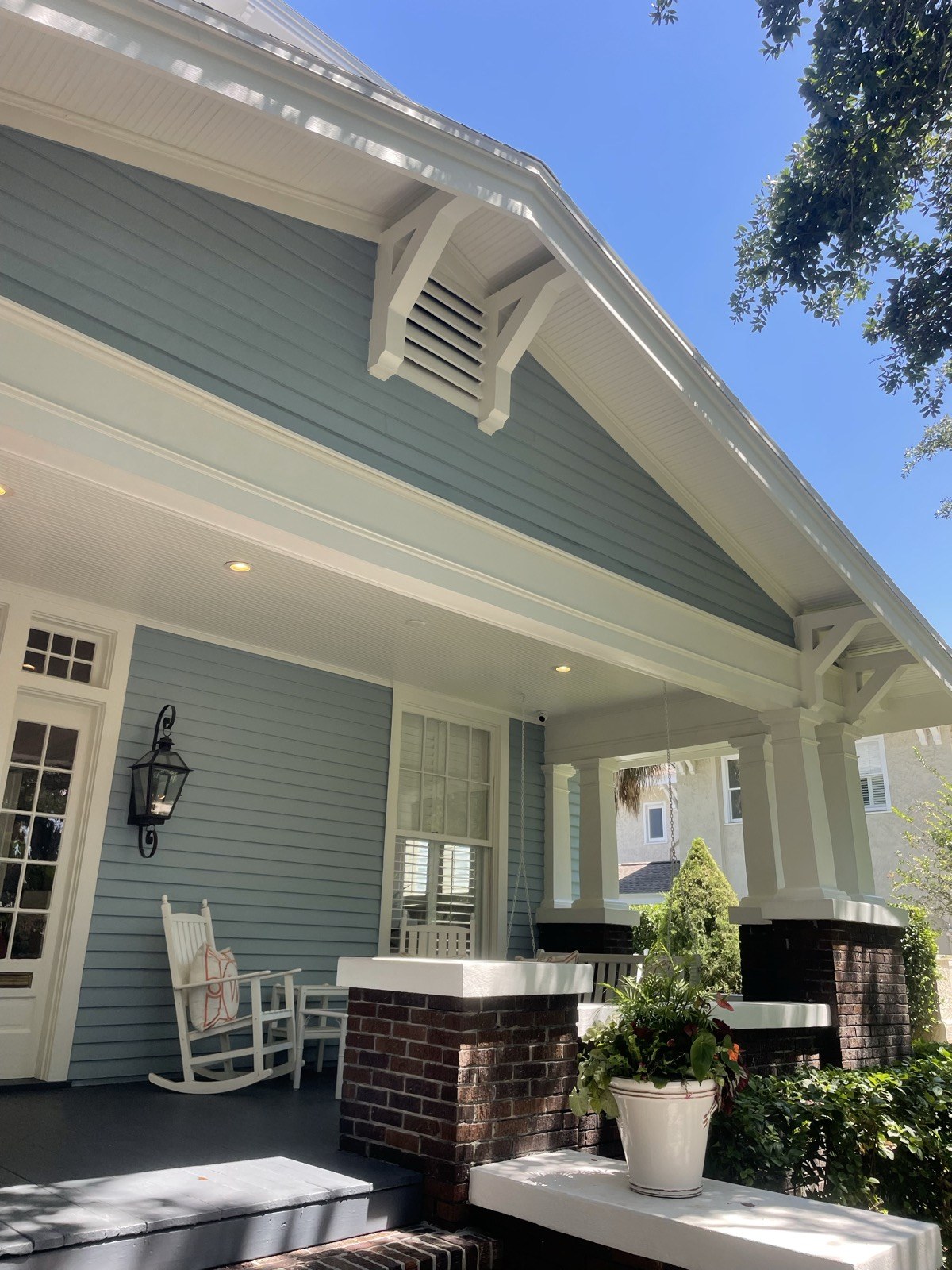 Blue craftsman porch with brick columns and white trim