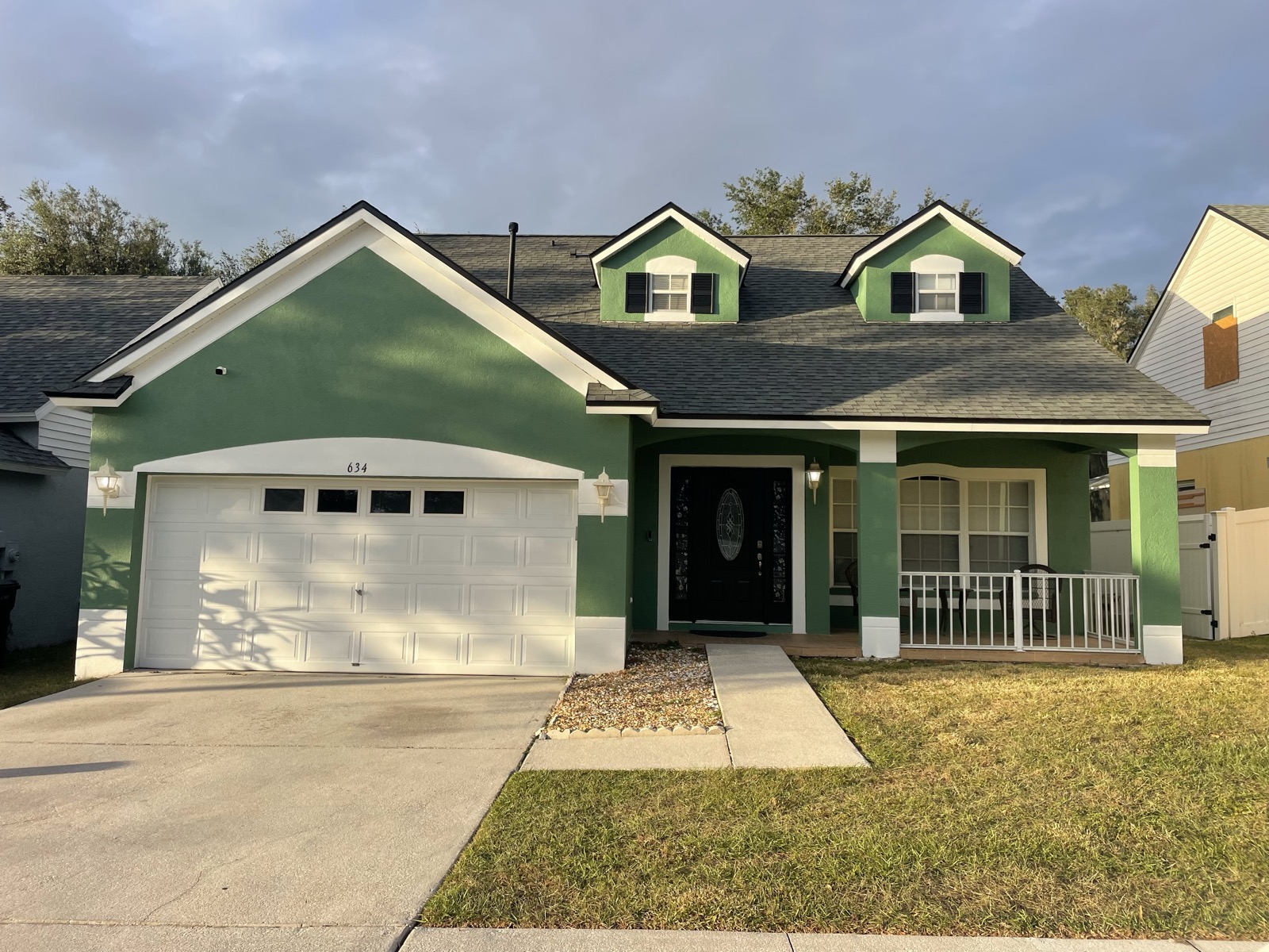 Green two-story home with white trim after repaint