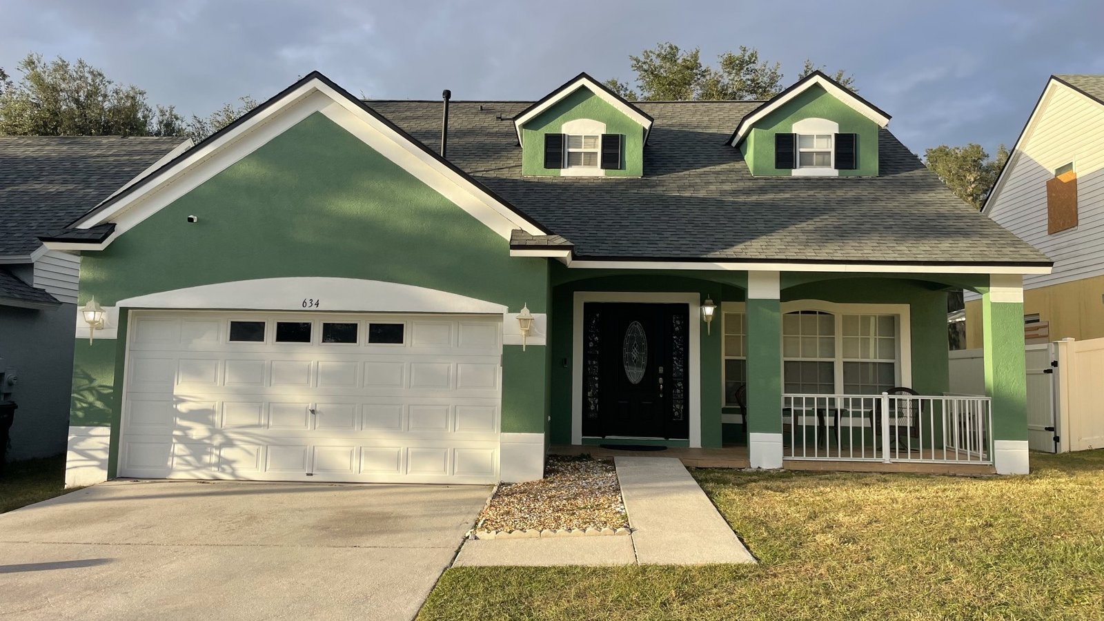 Freshly painted green two-story home with crisp white trim in Tampa Bay